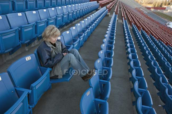 Reife kaukasische Frau sitzt allein im leeren Stadion — Stockfoto