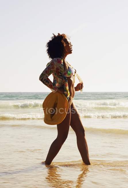 Женщина на пляже против волнистой воды — стоковое фото