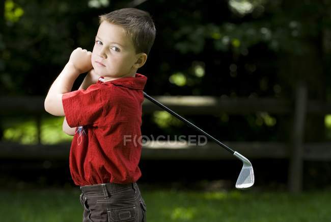 Jeune garçon caucasien avec club de golf au cours — Photo de stock