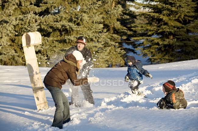Heureux caucasien famille jouer dans boules de neige sur hiver neige — Photo de stock