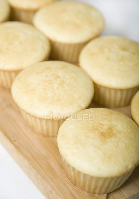 Muffins recién horneados en tablero de madera - foto de stock