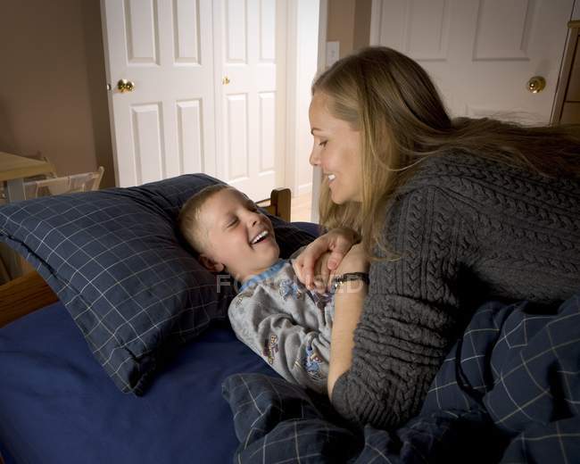 Carino ridendo madre e figlio in camera da letto — Foto stock
