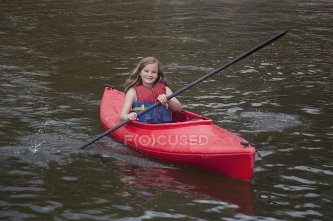 Chica en un kayak en la superficie del agua - foto de stock