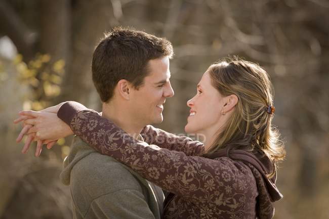 Attrayant couple heureux étreignant et se regardant dans le parc d'automne — Photo de stock