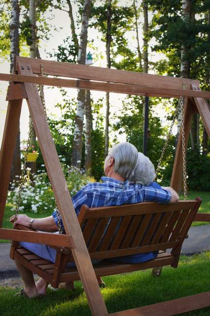 Senior couple sitting on swing, back view — Stock Photo