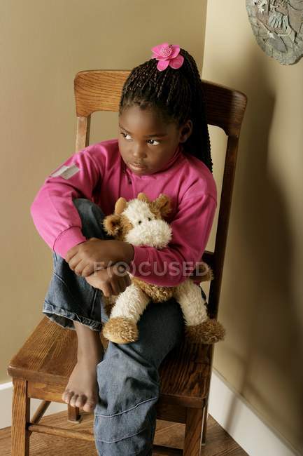 Menina triste sentada na cadeira no canto — Fotografia de Stock