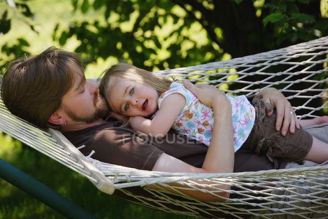 Отец и дочь отдыхают на гамаке — стоковое фото