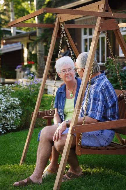 Seniorenpaar sitzt auf Schaukel und schaut sich an — Stockfoto