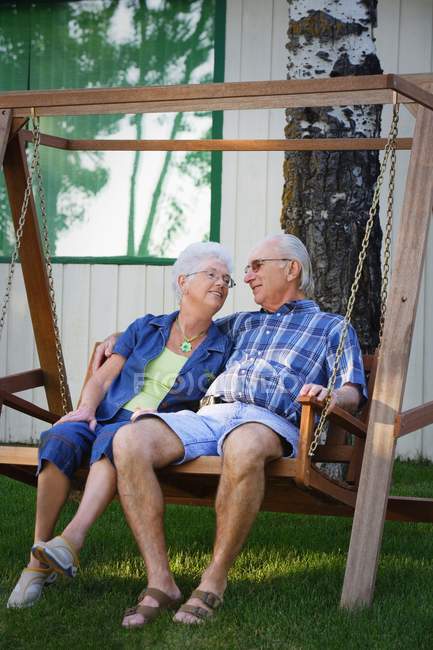 Старша пара сидить на гойдалках і дивиться один на одного — стокове фото