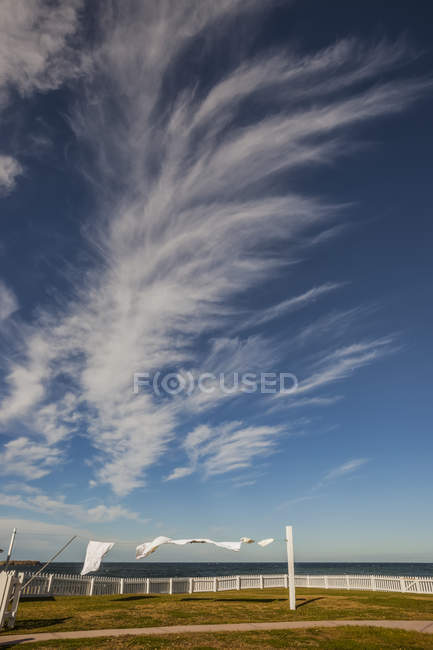Kleidung hängt am Seil über Feld mit weißem Holzzaun unter wolkenverhangenem Himmel — Stockfoto