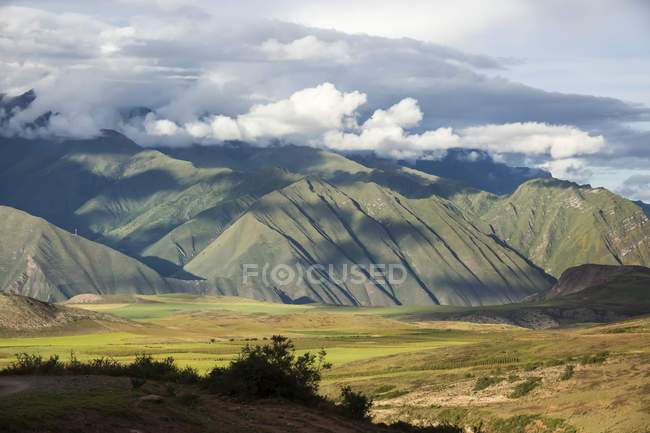 Green hills over valley against clouds in sky during daytime — Stock Photo