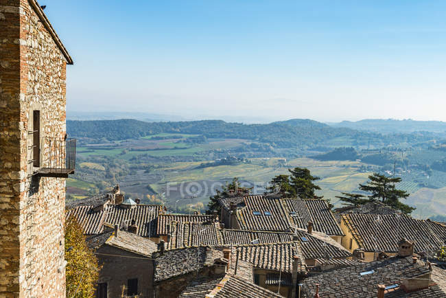 Panoramablick auf farbenfrohe toskanische Felder vor blauem Himmel und Ziegeldächer der Stadt Montepulciano; Toskana, Italien — Stockfoto