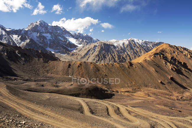 Route tortueuse de saleté de montagne de haute altitude, avec des montagnes couvertes de neige au loin ; Mendoza, Argentine — Photo de stock