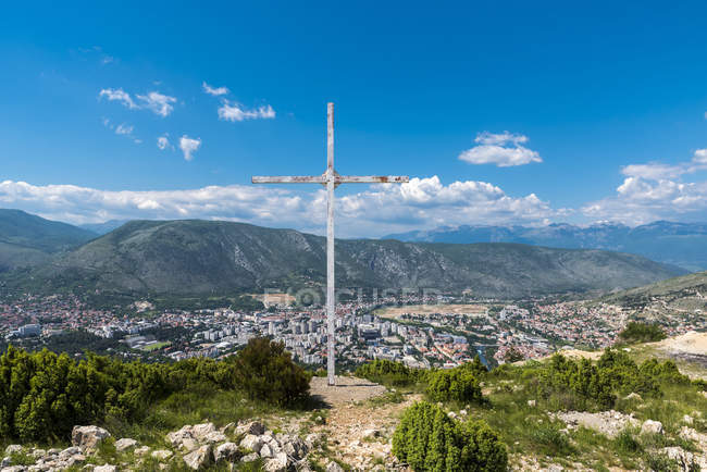 Ein Kreuz und Blick von der Spitze eines Berges, der Mostar überblickt und die Trennung der Stadt zeigt; Mostar, Bosnien und Herzegowina — Stockfoto