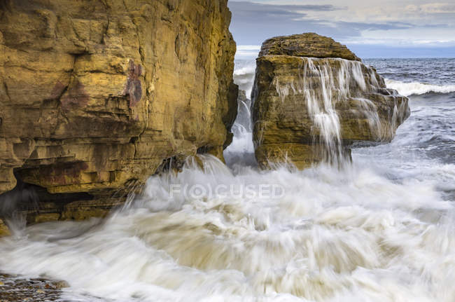 Хвиляста вода розбивається на скелястих скелях вдень — стокове фото