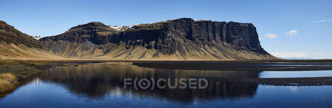 Rugged Cliffs Reflected In The Tranquil Water; Islanda — Foto stock