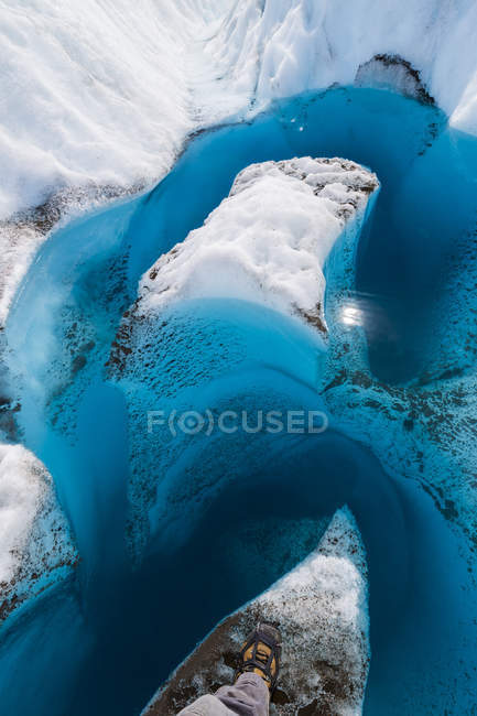 Vista del glaciar con formaciones en forma de arco y nieve, parte de la bota de persona en el suelo - foto de stock