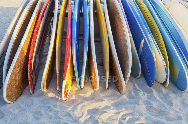Una pila de tablas de longboard coloridas colocadas en la playa,; Waikiki, Oahu, Hawaii, Estados Unidos de América - foto de stock
