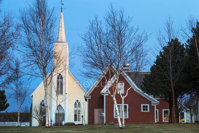 Una chiesa con campanile e edificio rosso al tramonto, Cavendish Beach; Cavendish, Prince Edward Island, Canada — Foto stock