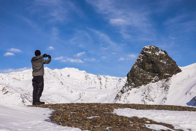 Male hiker making photo of mountains peaks on smartphone during daytime — Stock Photo