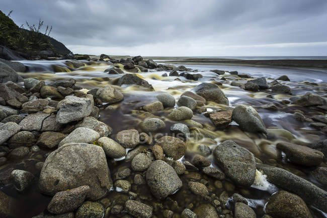 Beaucoup de pierres sur le rivage contre l'eau de mer pendant la journée — Photo de stock