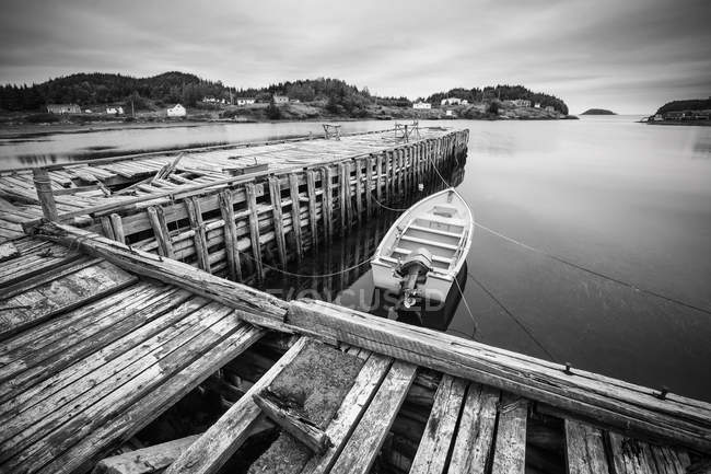 View of wooden dock with moored boat over water, balck and white picture — Stock Photo
