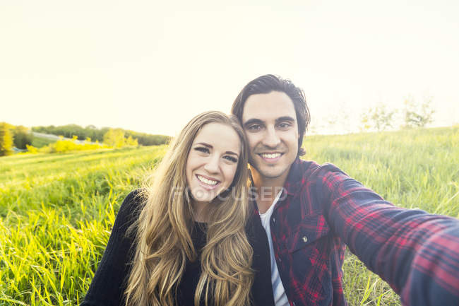 Щасливі романтична пара, роблячи sefie на відкритому повітрі над зеленою травою і посміхаючись камери — стокове фото