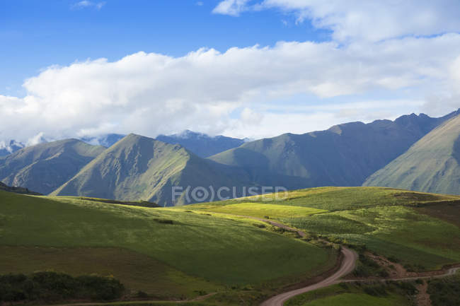 Green grass valley with peaks on background during daytime — Stock Photo