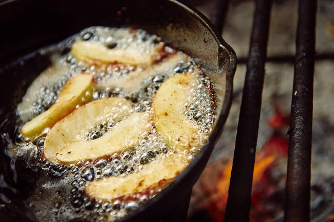 Fette di mela cotte in una padella su una griglia su una fiamma aperta; Ontario, Canada — Foto stock