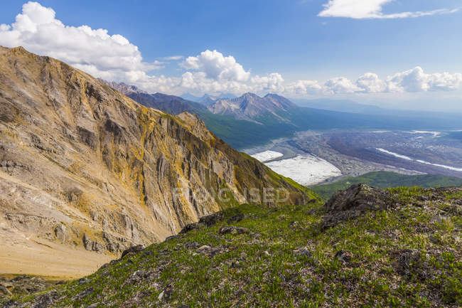 View of mountain slope with green grass and peaks with valley on foot on background — Stock Photo