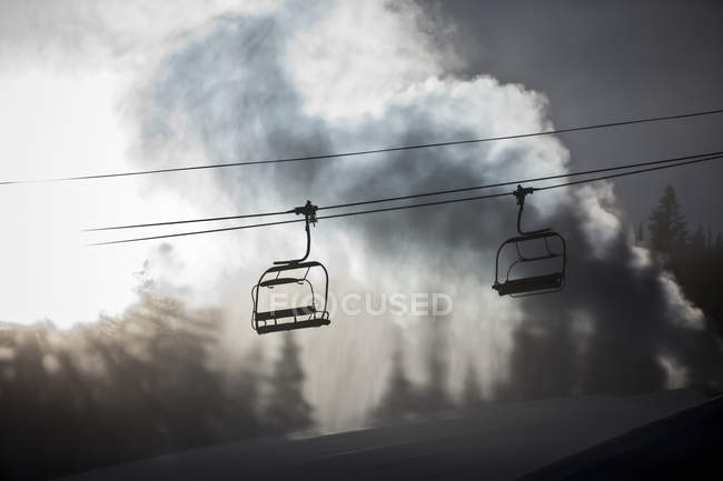 Funivia con cabine contro cielo nuvoloso e alberi durante il giorno — Foto stock