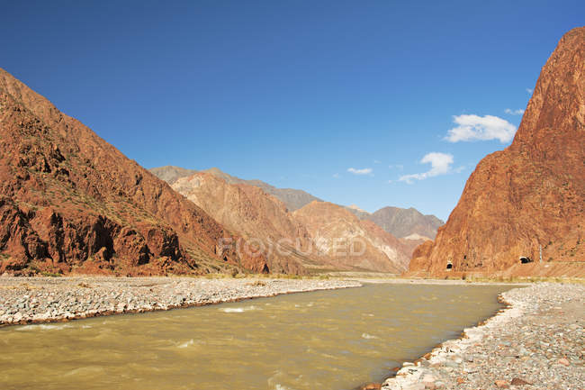 Um rio serpentes através de montanhas coloridas nos Andes secos, dois túneis rodoviários são visíveis; Mendoza, Argentina — Fotografia de Stock