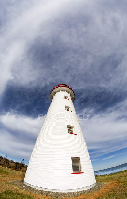 Vue à angle bas du phare debout sur le rivage contre l'eau pendant la journée — Photo de stock