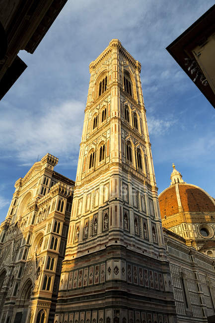Grande cathédrale décorative avec tour et dôme avec ciel bleu et nuages orange brillant au coucher du soleil, cathédrale florence, Italie — Photo de stock