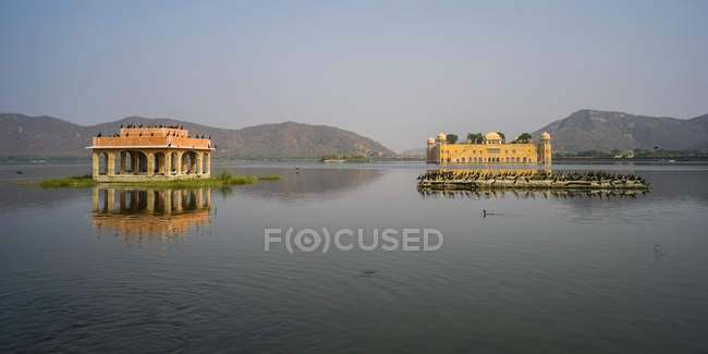 Palacio de Jal Mahal, hecho de piedra arenisca roja, sentado sumergido en el lago Man Sagar; Jaipur, Rajastán, India - foto de stock