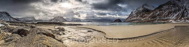 A landscape with rugged mountains and sand along the coastline under a cloudy sky; Nordland, Norway — Stock Photo