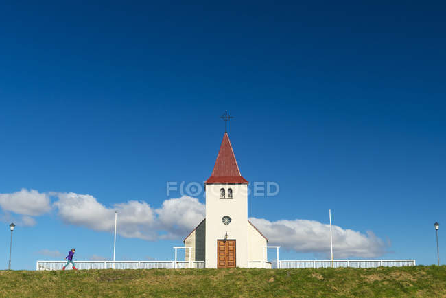 Chica caminando por la pequeña iglesia; Langaholt, Islandia - foto de stock