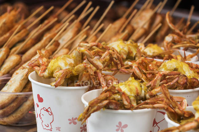Vista de cerca de los tradicionales mariscos asiáticos fritos en vasos de papel - foto de stock