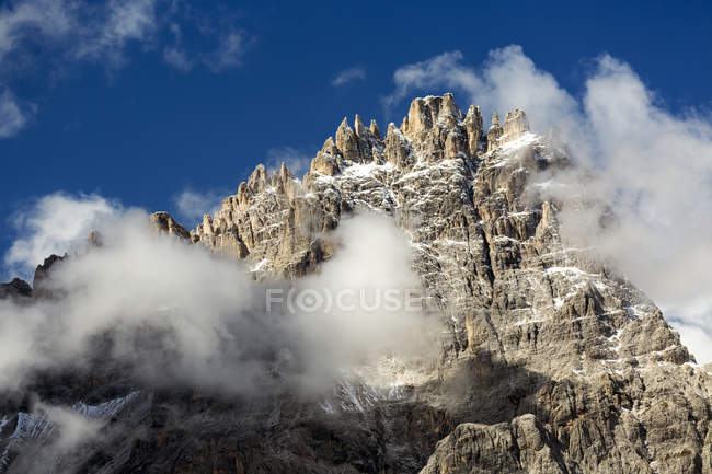 Schroffe Bergspitze aus Wolken mit blauem Himmel; sesto, Bozen, Italien — Stockfoto