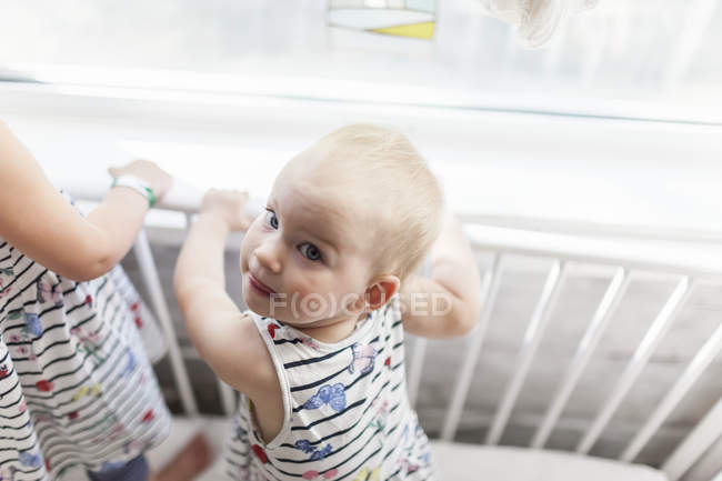 Two sisters playing together in crib by window — Stock Photo