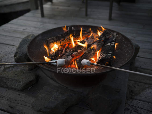 A fire pit on a wooden deck with marshmallows roasting; Lake of the Woods, Ontario, Canada — Stock Photo