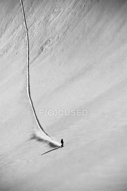 A professional, freeriding snowboarder on a wide open snowy slope making new tracks; British Columbia, Canada — Stock Photo