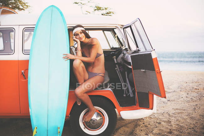 Estilo de vida de playa, hermosa chica surfista con clásico Vintage Surf Van en la playa al atardecer - foto de stock