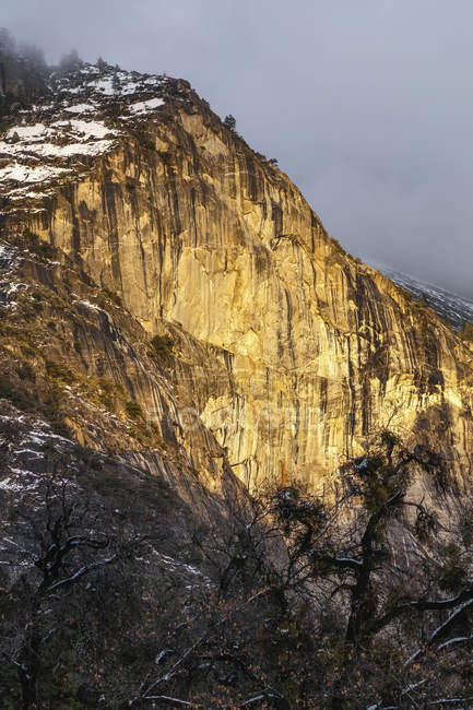 Pared de granito Yosemite iluminada con luz solar dorada, Parque Nacional Yosemite; California, Estados Unidos de América - foto de stock