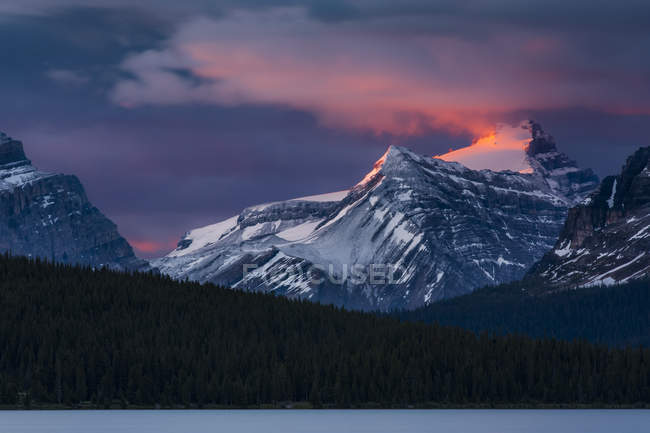 Salida del sol iluminando los picos de las Montañas Rocosas sobre el Lago Bow, Parque Nacional Banff; Distrito de Mejoramiento No. 9, Alberta, Canadá - foto de stock