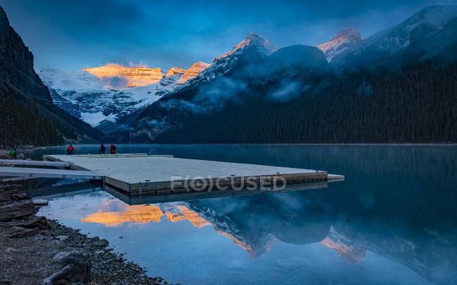 Picos das Montanhas Rochosas iluminados pela luz solar e refletidos no Lago Louise; Lago Louise, Alberta, Canadá — Fotografia de Stock