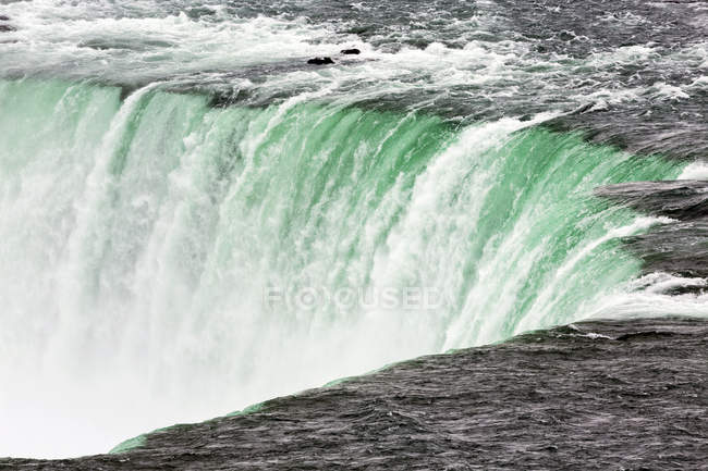 Close up view of Niagara Falls in Ontario with the turquoise coloured water flowing over the edge; Niagara Falls, Ontario, Canada — Stock Photo
