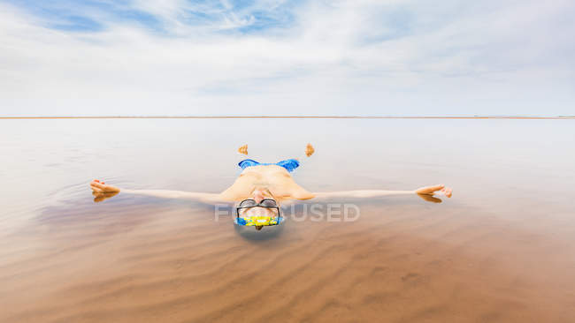Homem vestindo roupa de banho flutuando na água do mar rasa — Fotografia de Stock