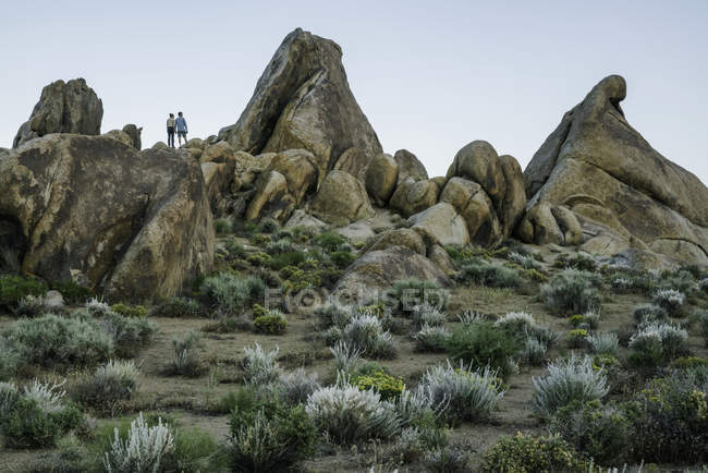 Coppia in piedi sulle rocce dell'Alabama Hills dopo il tramonto; California, Stati Uniti d'America — Foto stock