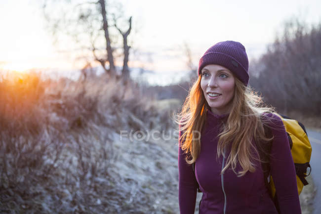 Una giovane donna che porta uno zaino e cammina all'alba; Anchorage, Alaska, Stati Uniti d'America — Foto stock